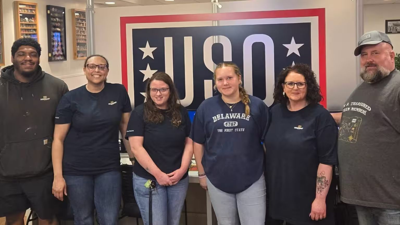 Team standing in front of a USO volunteer sign