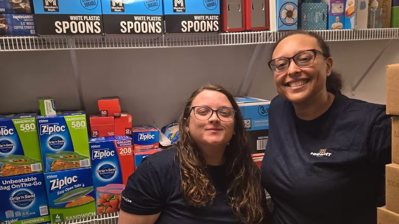 Two ladies standing in front of donated items on a shelf