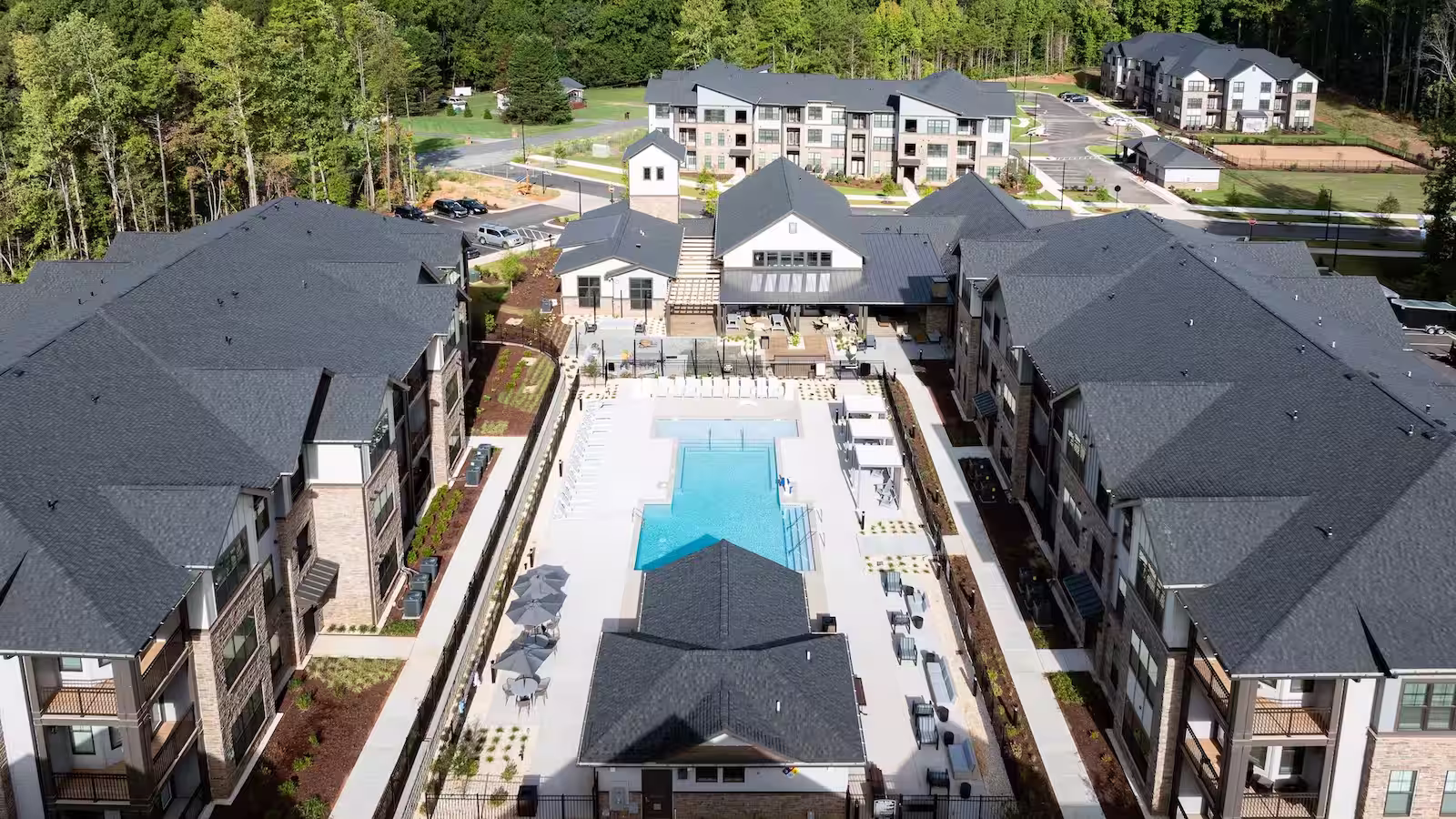 A drone photo of an apartment community with a pool in the middle