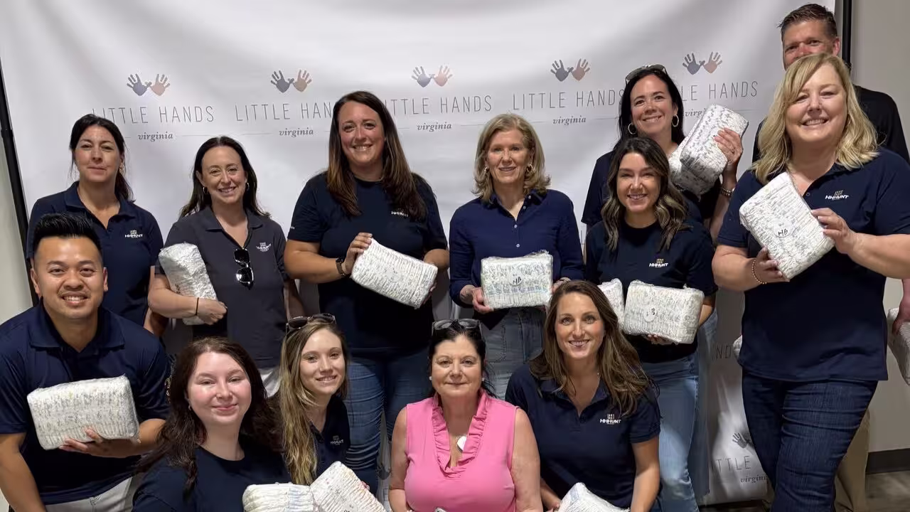 Group of male and female team members smiling for a photo while holding baby diapers