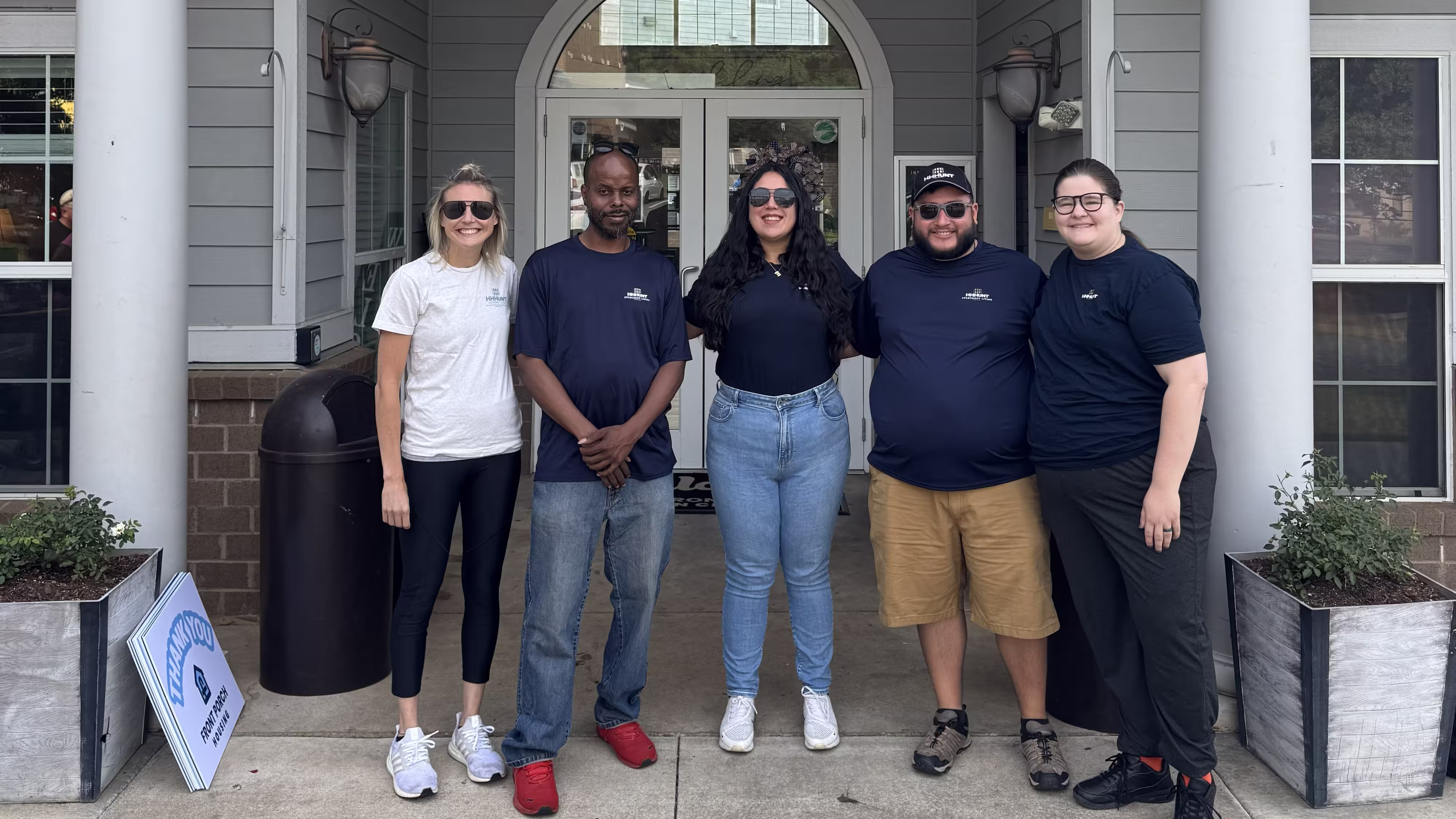 Five people standing in front of a fancy house.