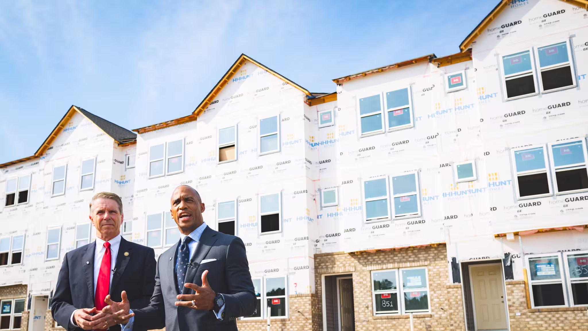 HUD Secretary and Congressman standing in front of a home under construction.