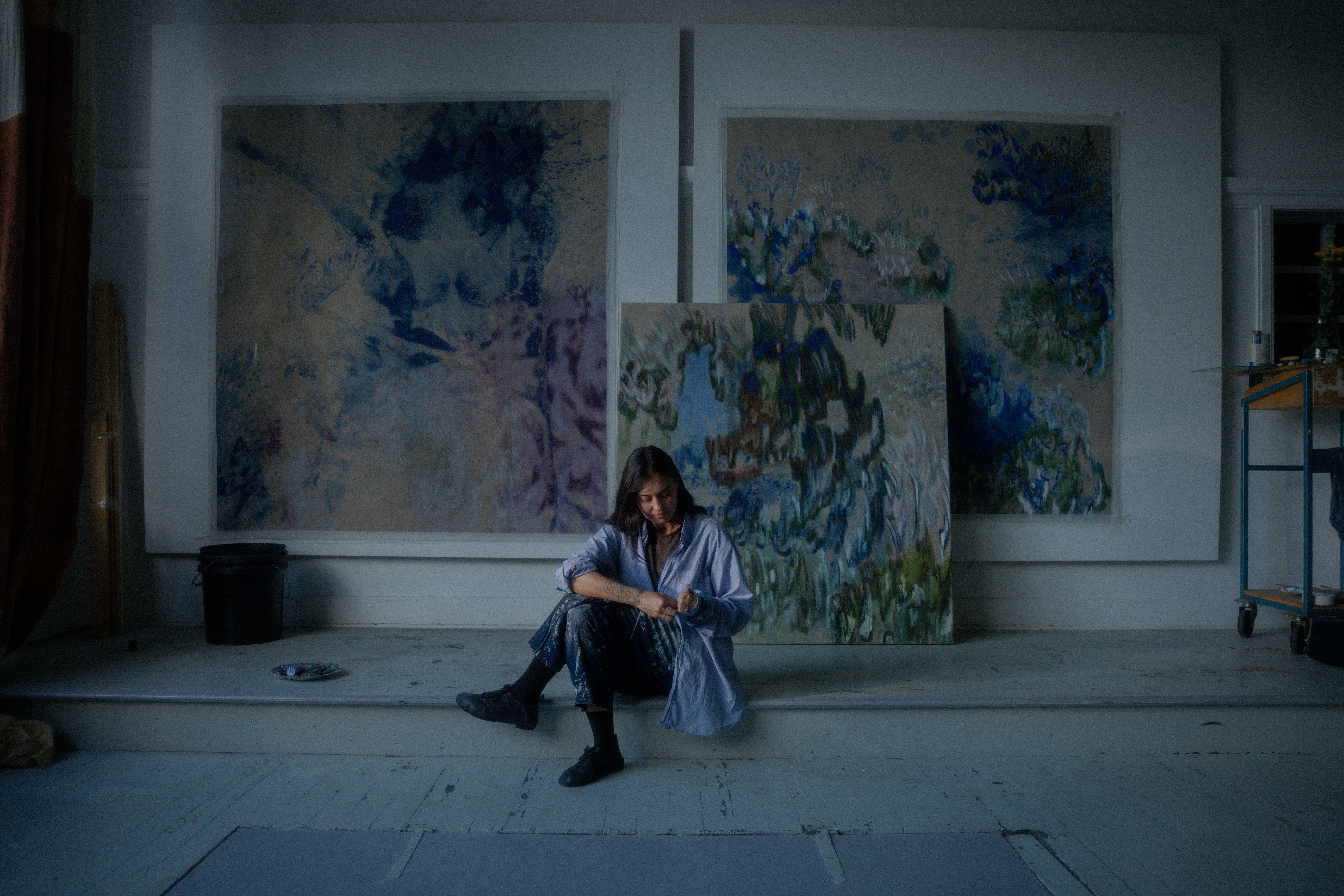 Eline sitting in front of her paintings