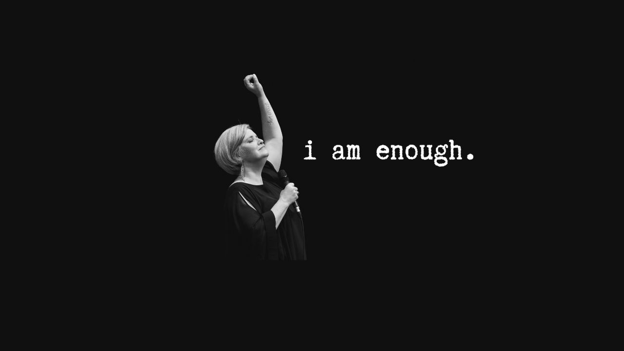 Black background with a woman photographed in B&W raising her arm in solidarity.