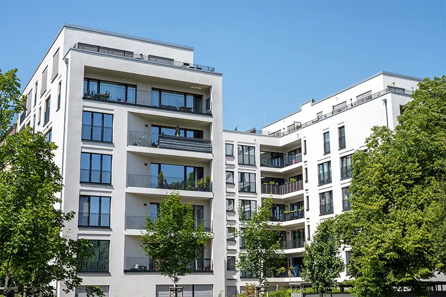 Contemporary apartment building with balconies in a lush green setting, ideal for Airbnb rentals in urban areas.