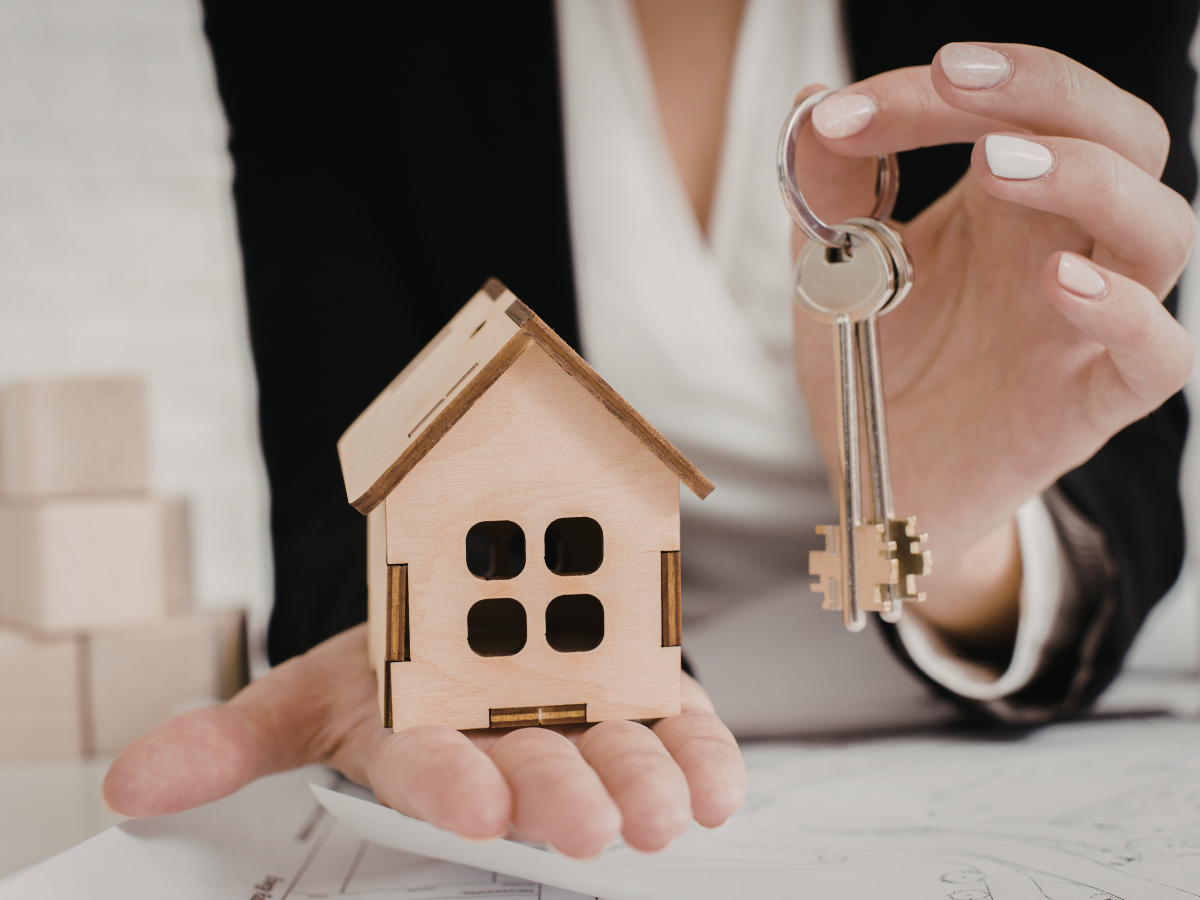 A woman holding a set of keys and a mock tiny house
