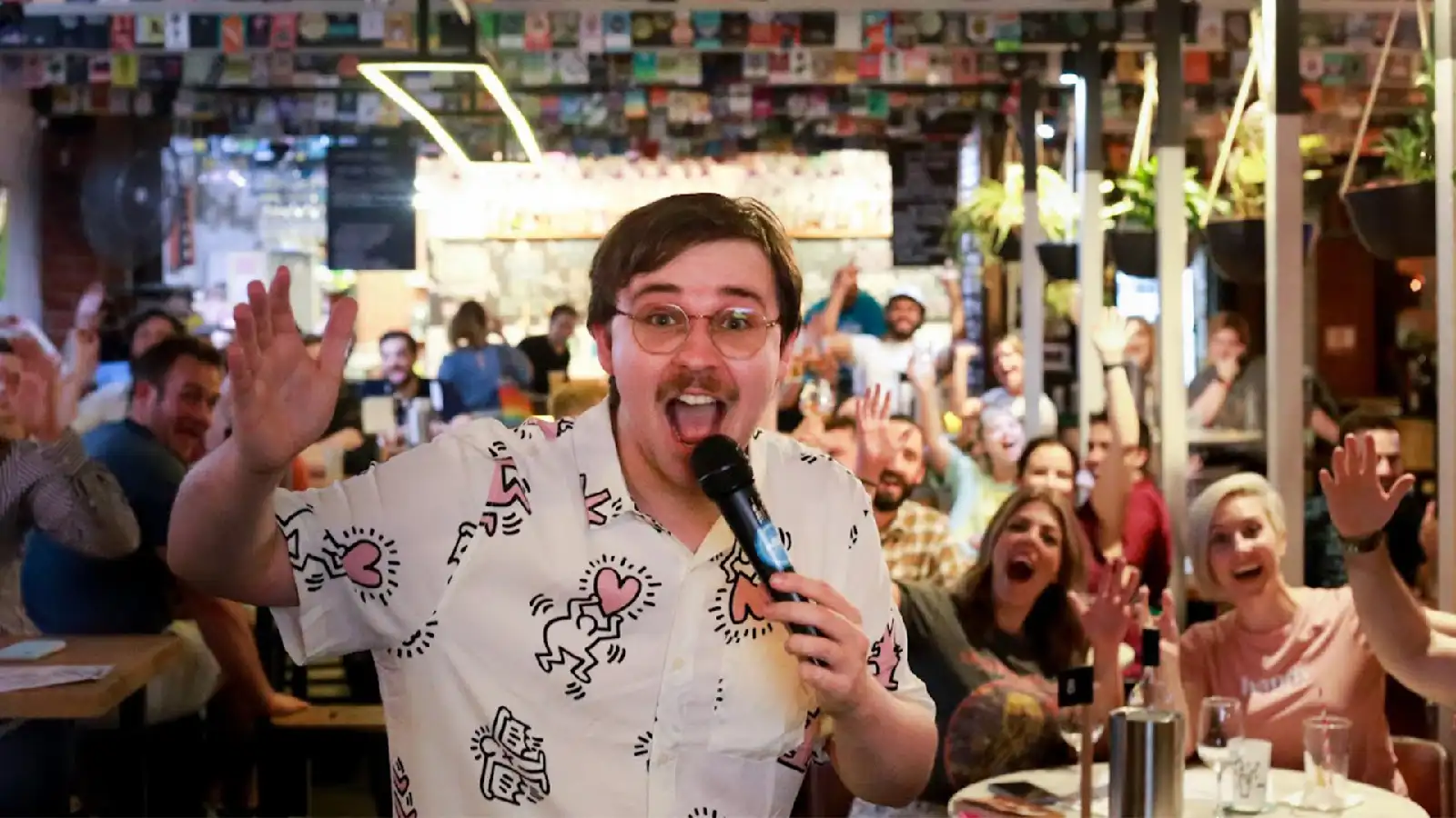 Photo of a host holding a microphone in front of an excited cheering bingo crowd.