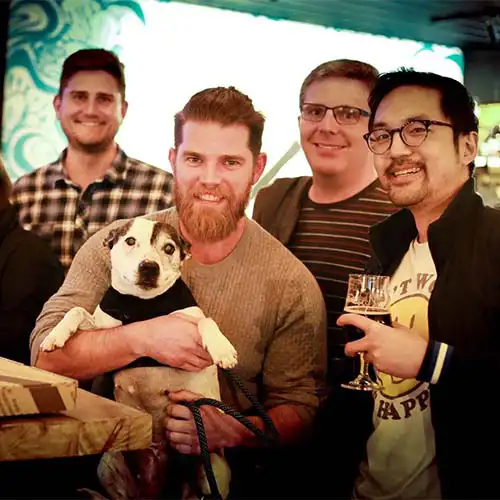 A team gathers around for a photo holding their dog at a Quiz Meisters trivia show