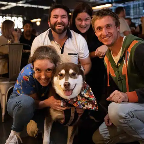 A team at a Quiz Meisters trivia show gathers around their dog for a photo
