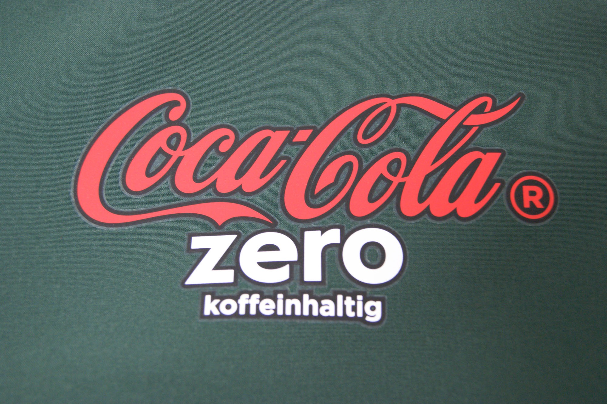 Coca-Cola Logo in rot auf grünem Textil