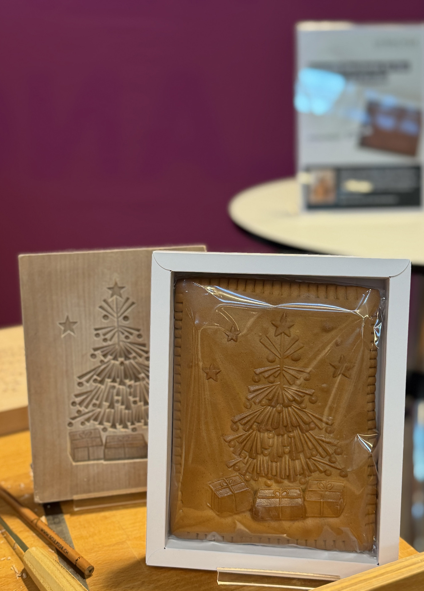 Leibacher Biber mit eingeprägtem Tannenbaum-Motiv in einem weissen Rahmen, daneben das geschnitzte Holzmodel