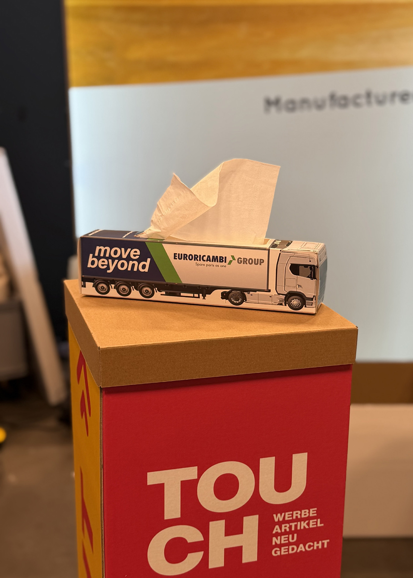 Taschentuchbox in Form eines Sattelschleppers mit Firmenbranding, aus dem Auflieger ragt ein Taschentuch