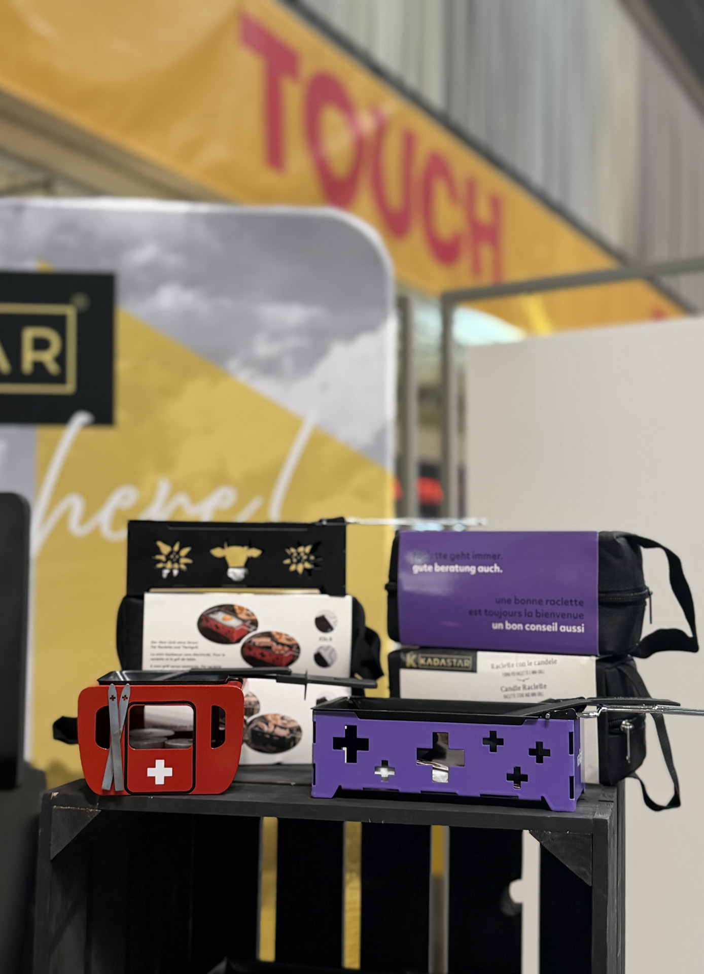 Mehrere Kerzenraclettes in Rot mit Schweizerkreuz und in Violett mit Ausstanzungen, dazu die Geschenkverpackungen