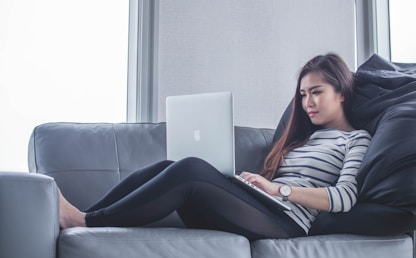 Femme concentrée apprenant l'anglais sur son ordinateur portable depuis son canapé
