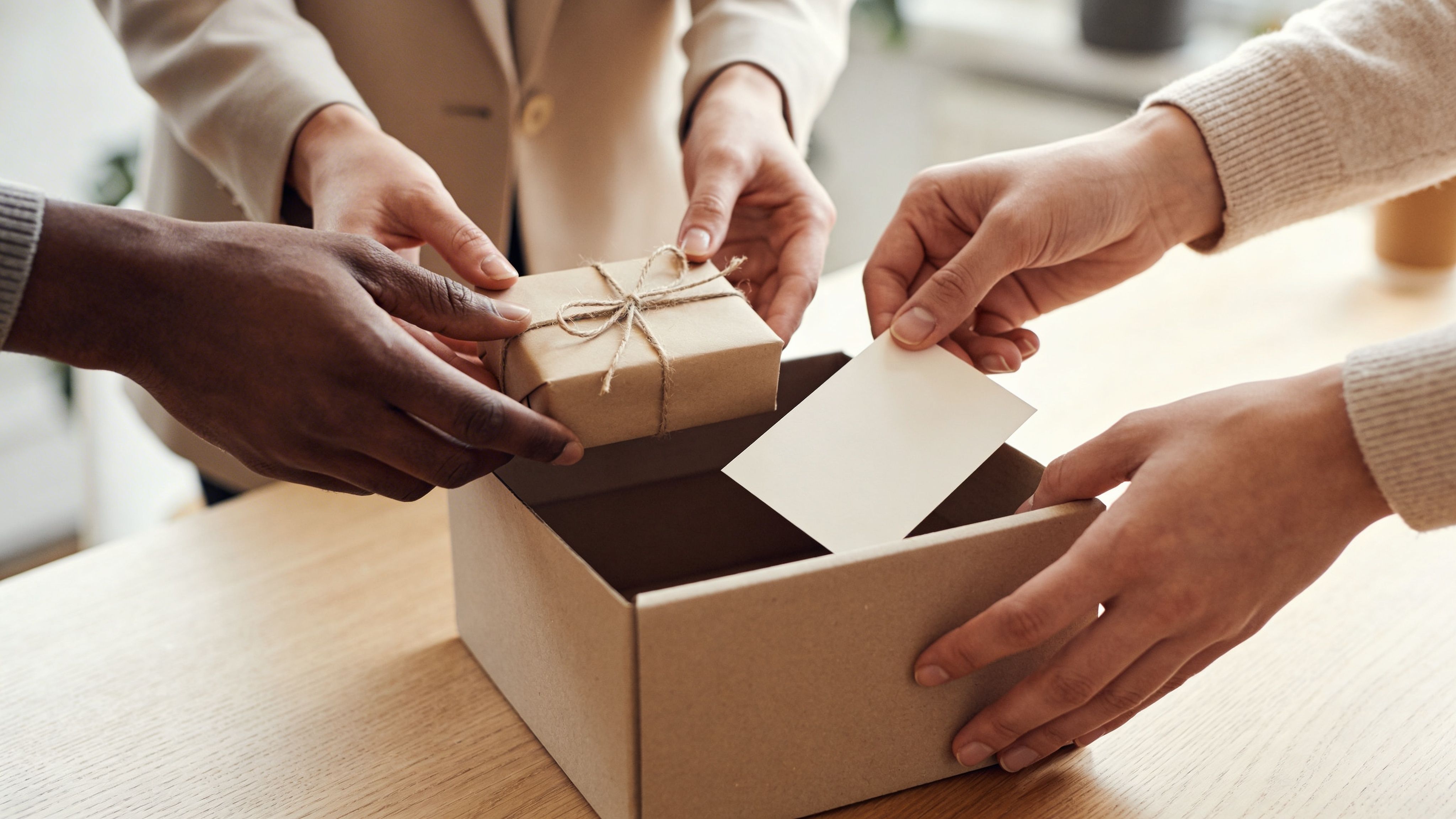 Un grupo de compañeros de trabajo coloca un regalo envuelto en papel craft dentro de una caja