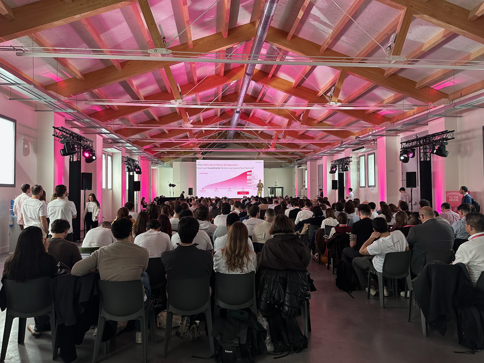more than 100 people seated in a large auditorium during a conference