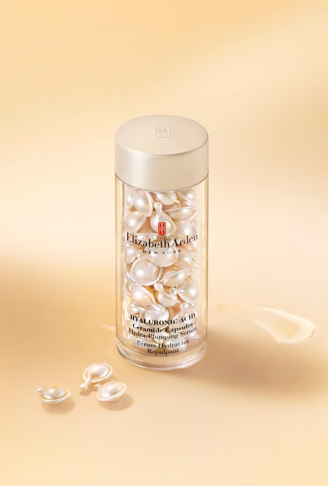 Clear bottle filled with pearl-shaped capsules labeled Elizabeth Arden Hyaluronic Acid Ceramide Capsules Hydra-Plumping Serum.