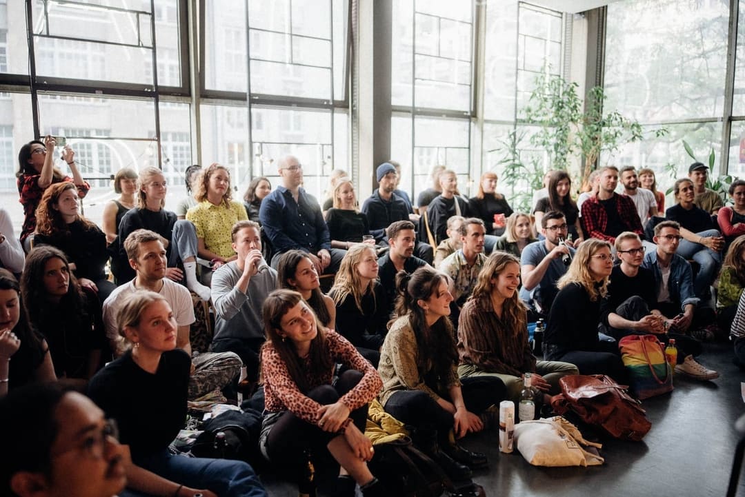 female business entrepreneur siting and talking with a male community manager in front of a green door of betahaus kreuzberg coworking space