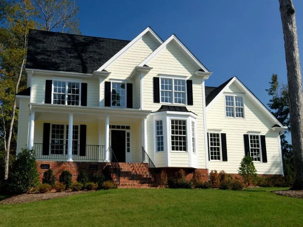 light siding home under tree green lawn blue sky