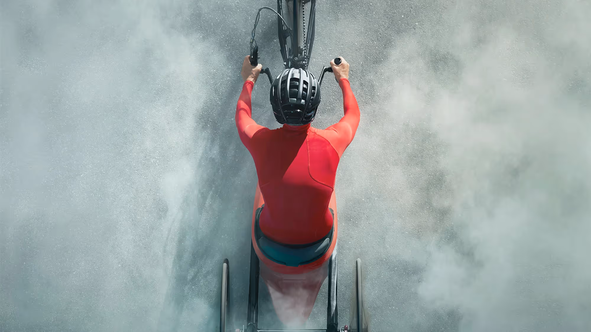 A photo of a Paralympic cyclist, shot from above. The cyclist is surrounded by dust from the bicycle.