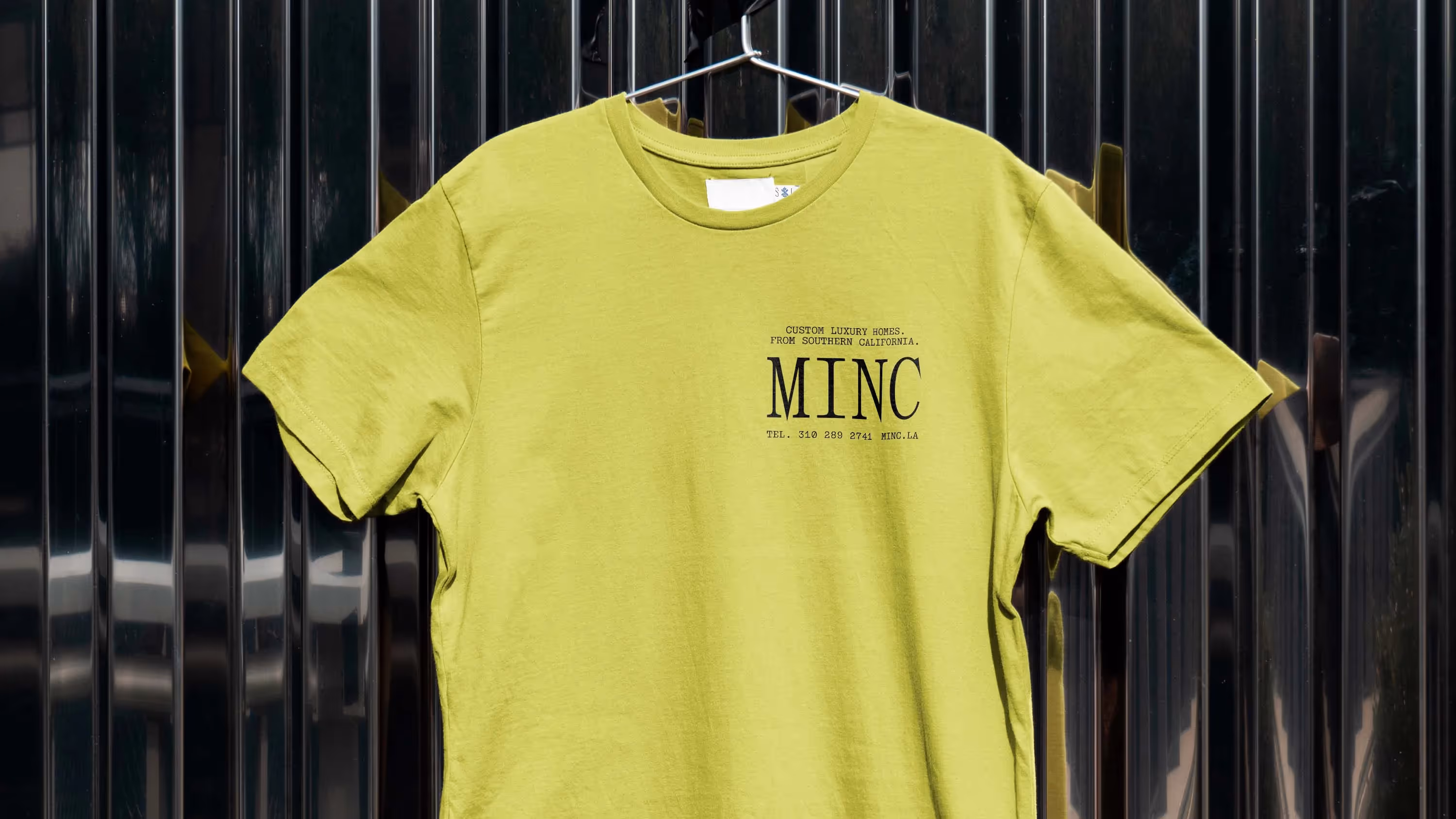 A Minc-branded work T-shirt hanging on a wall.