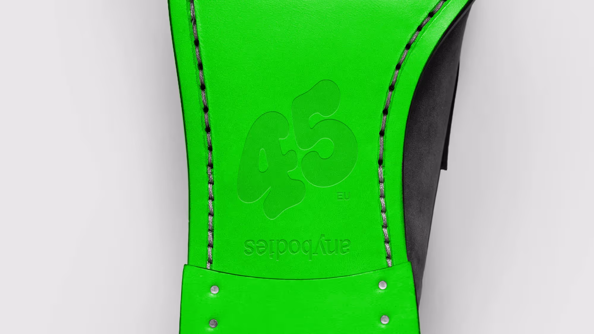The sole of an Anybodies-branded shoe. The sole is fluorescent green and the size is debossed into it.