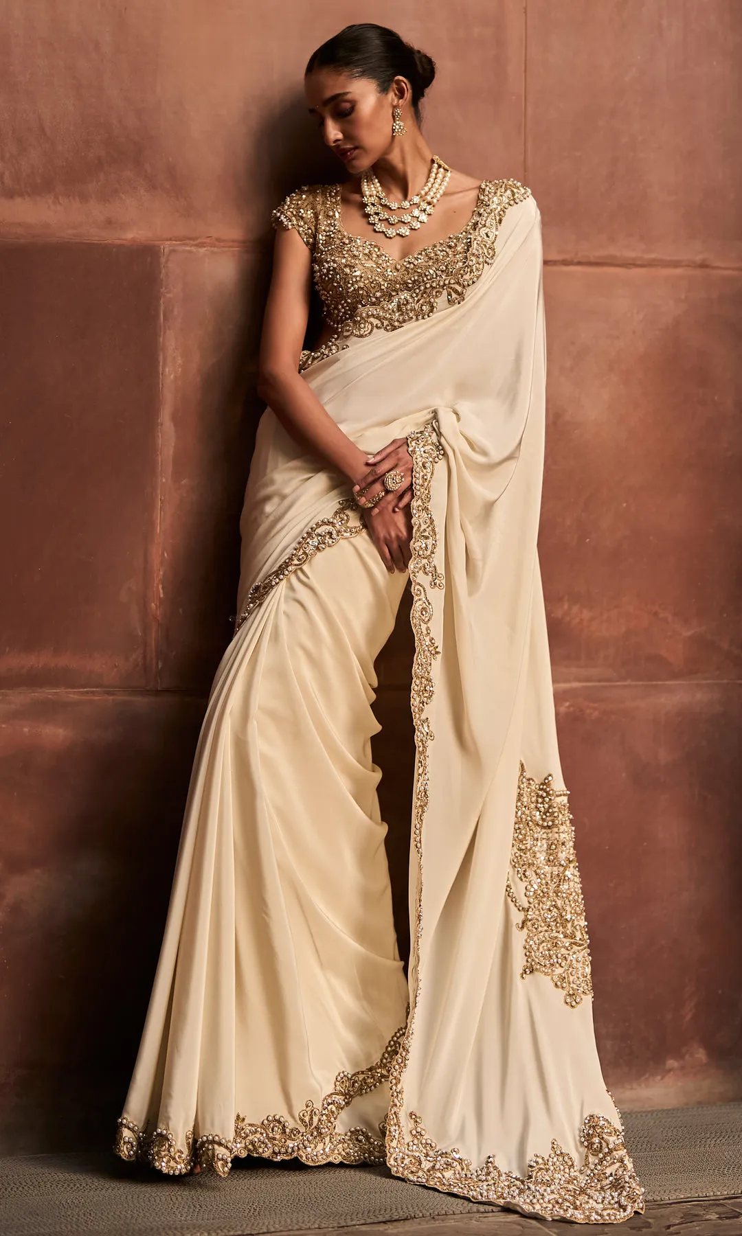 Zameen-e-Noor is a regal bridal sharara ensemble crafted in a rich antique gold tone, celebrating traditional craftsmanship with timeless elegance. The voluminous sharara pants are adorned with intricate all-over hand embroidery featuring geometric and floral motifs, highlighted with zardozi, sequins, and fine beadwork. Paired with a heavily embellished short kurta and finished with a delicately embroidered sheer dupatta, this ensemble exudes ceremonial grandeur. Designed for brides seeking heritage luxury with a distinguished silhouette, it is an ode to classic bridal opulence.