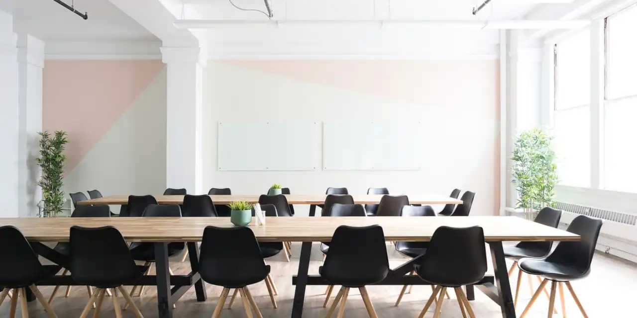 Bright meeting room with a long wooden table and black chairs