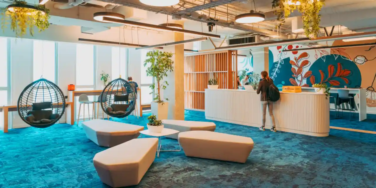 Open lounge with hanging chairs, seating islands and a reception counter in front of a painted wall