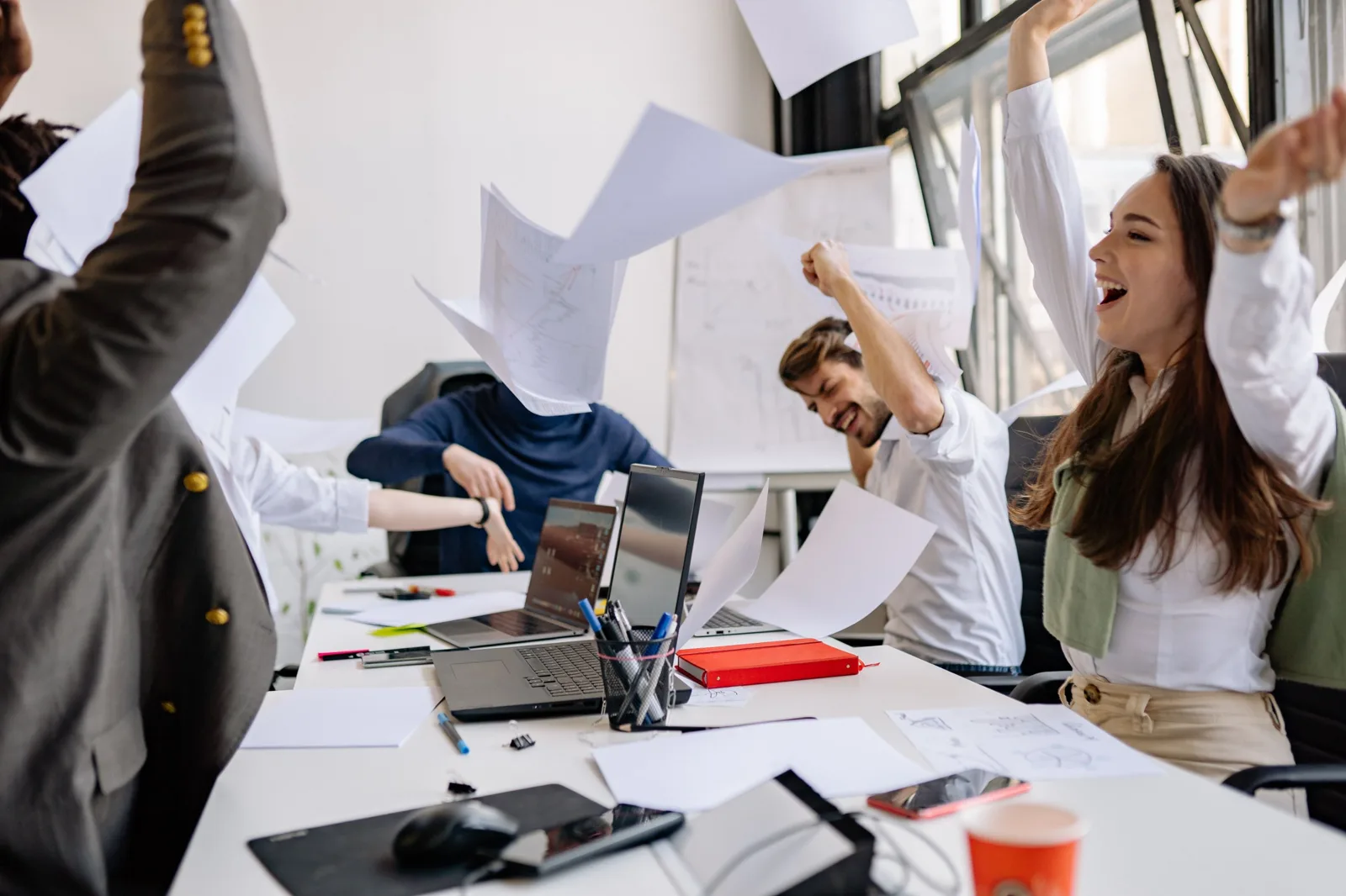 Team im Büro wirft jubelnd Papiere in die Luft