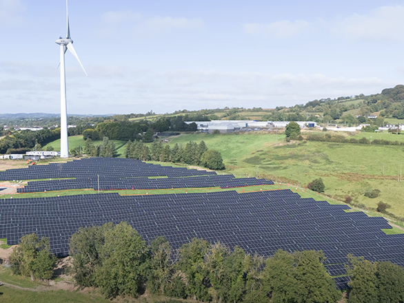 Solar farm at Liffey Meats facility with wind turbine and countryside landscape