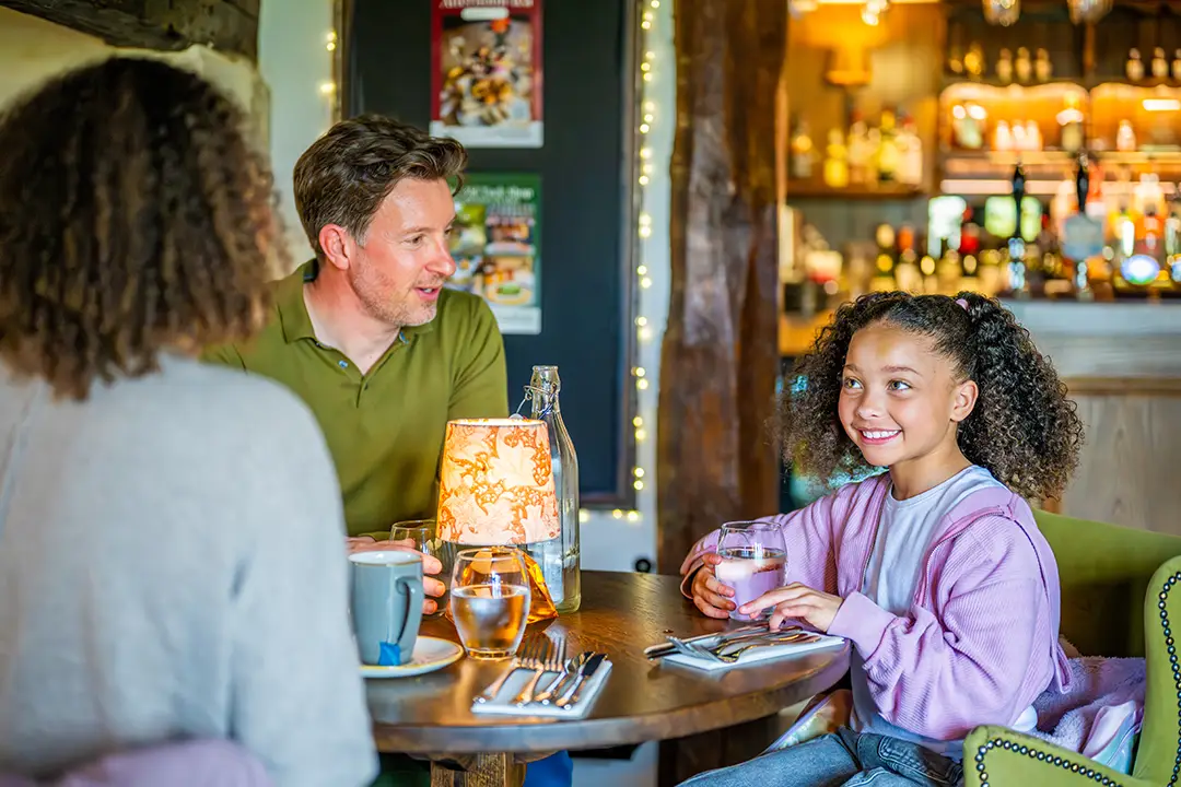 Family around a dinner table having drinks ahead of their meal at The Royal Oak in Barrington, Cambridgeshire.