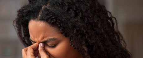 Woman experiencing sinus pressure and nasal pain, holding her face with discomfort