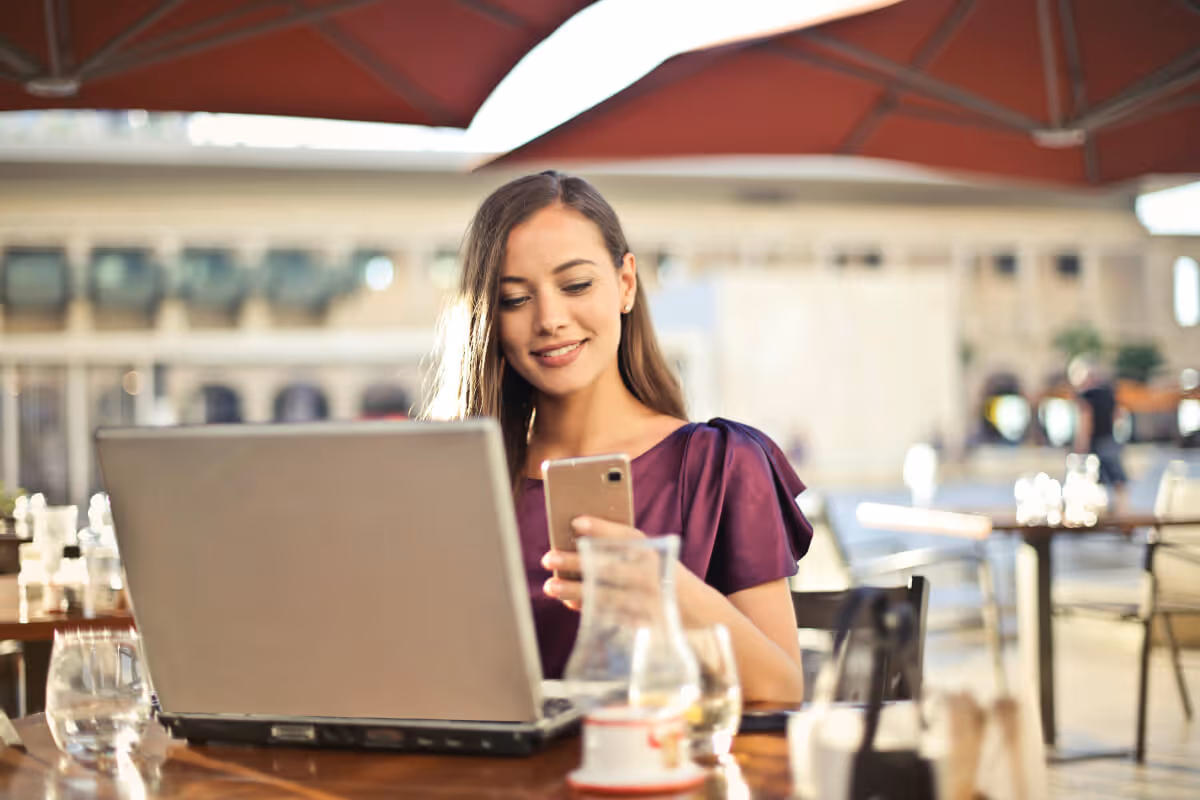 A woman sitting at an outside table, looking at her phone.