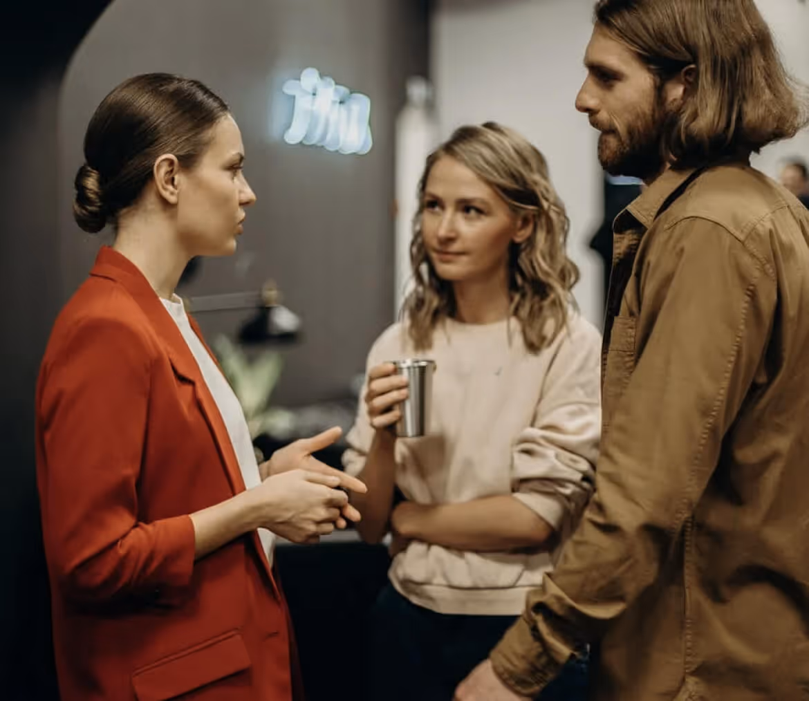 Three people having a discussion in a lounge room.