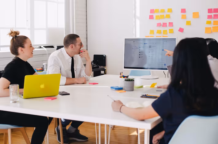 Team members having a meeting. Looking at a computer monitor. 