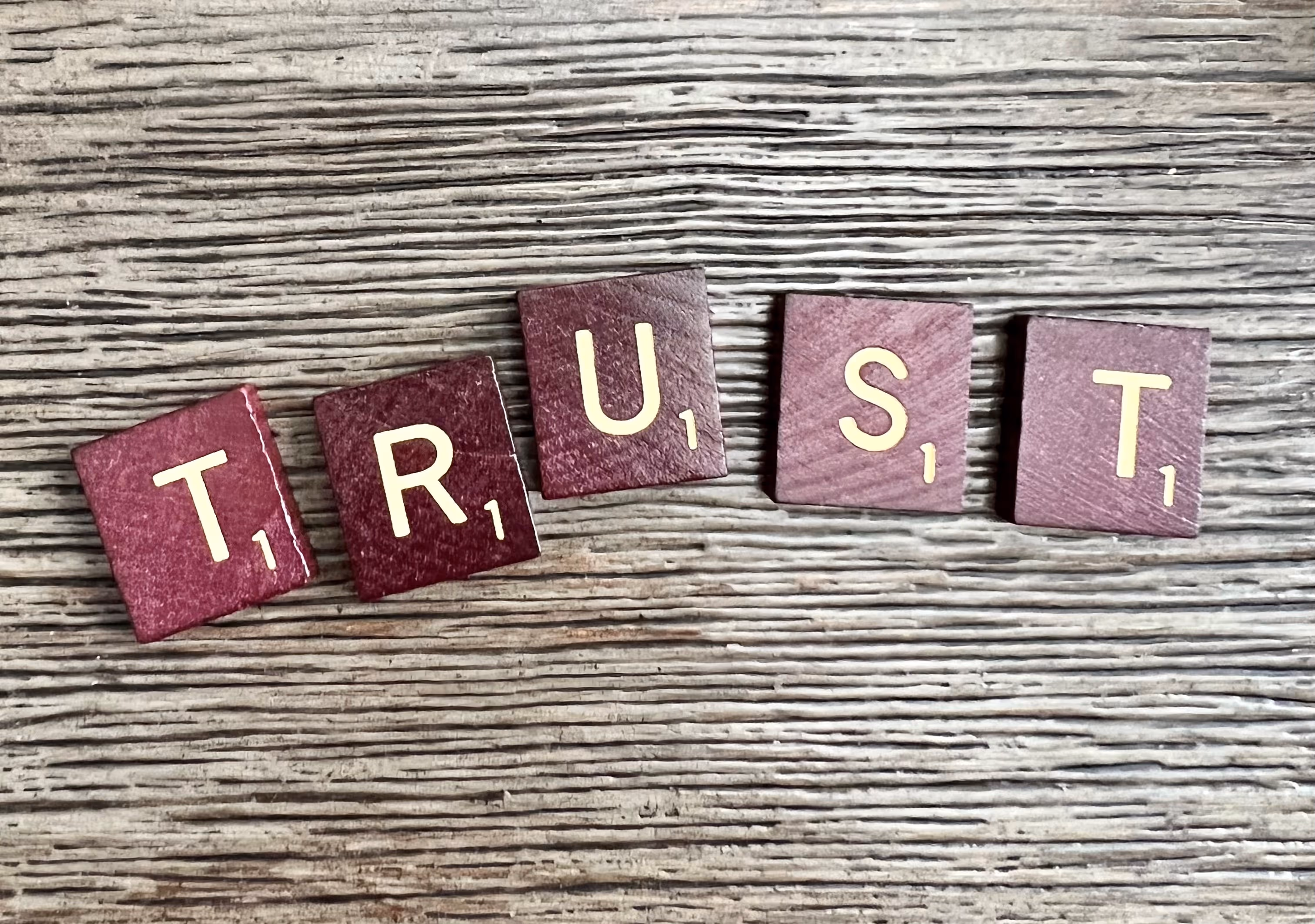 scrabble pieces laid out to spell the word trust.