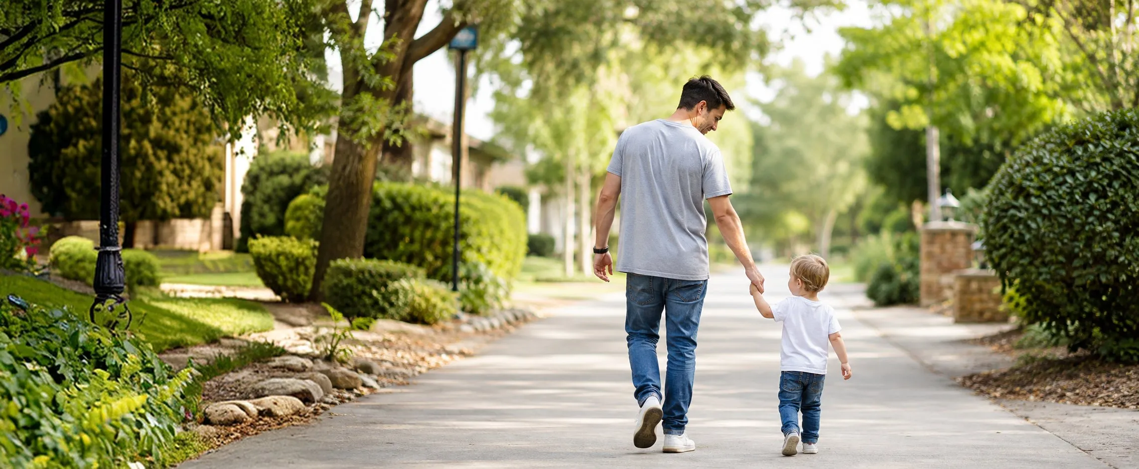 Father walking hand in hand with his child on a Texas neighborhood sidewalk
