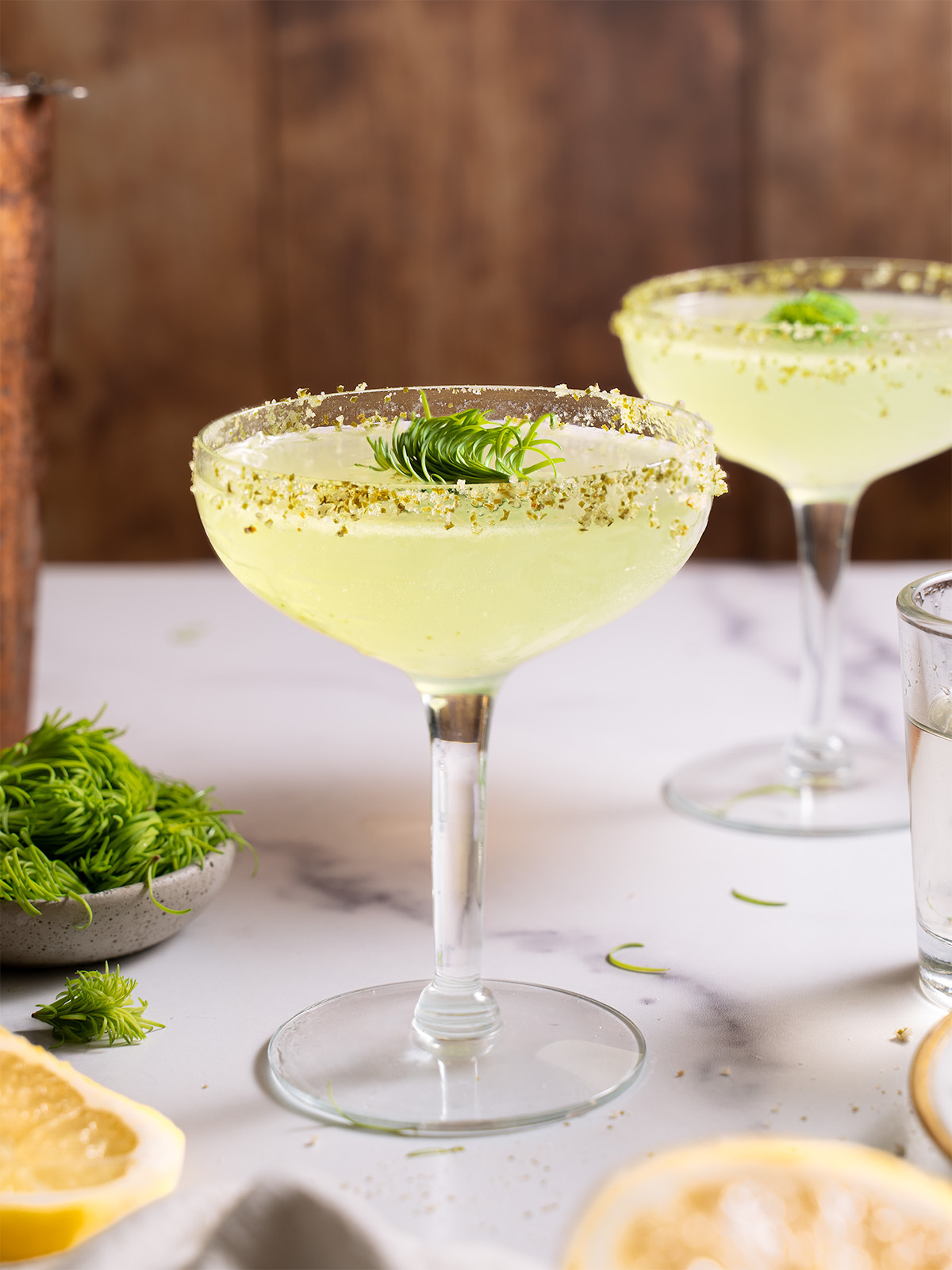 A coupe cocktail glass filled with Fir Tip Lemon Drop Martini
