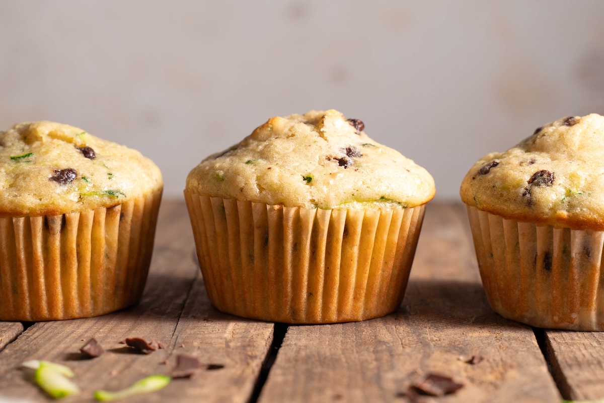 Three sourdough zucchini chocolate chip muffins lined up in a row