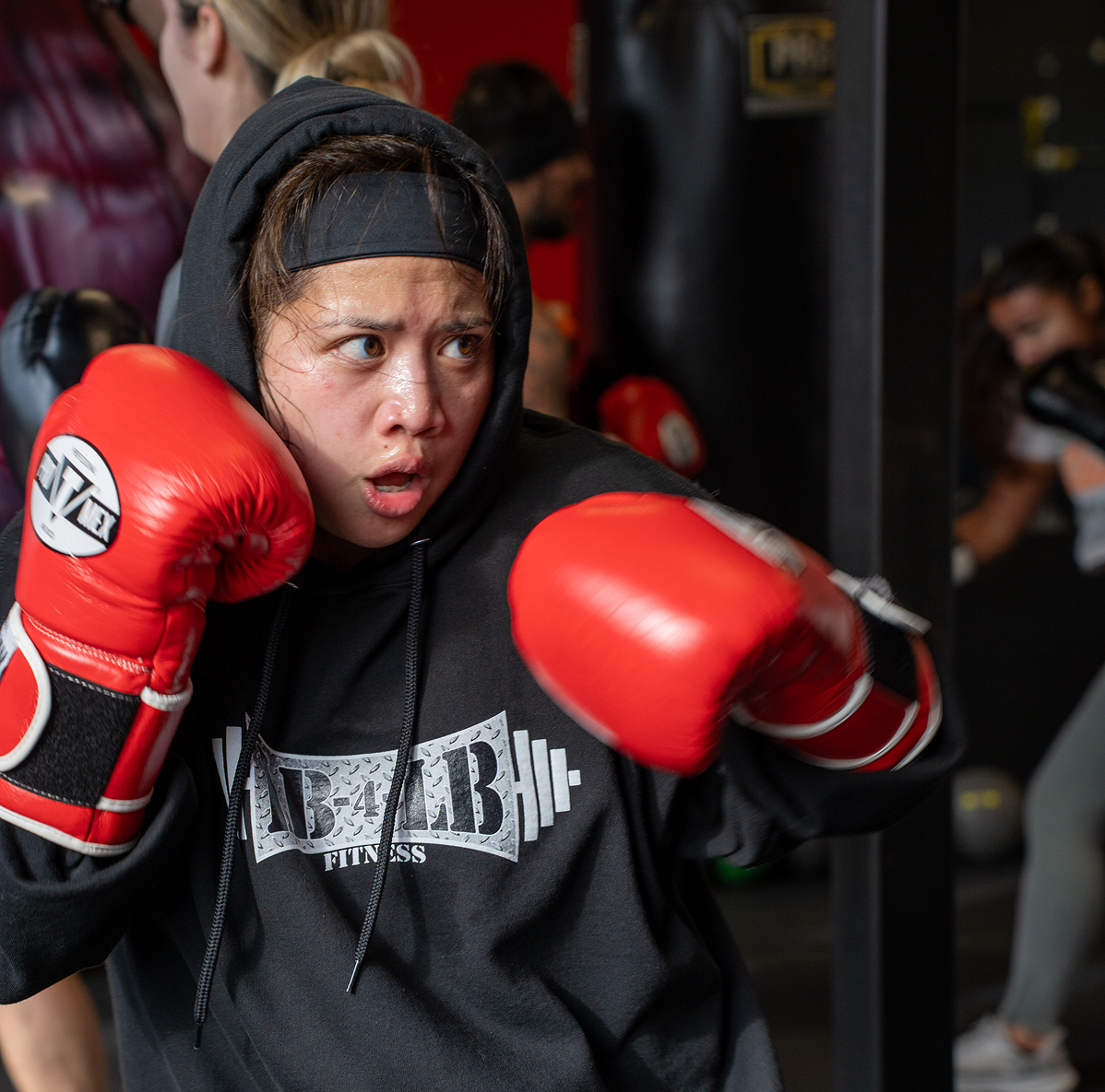 Gym member completes workout with a dumbbell raised above her shoulder in lunge position