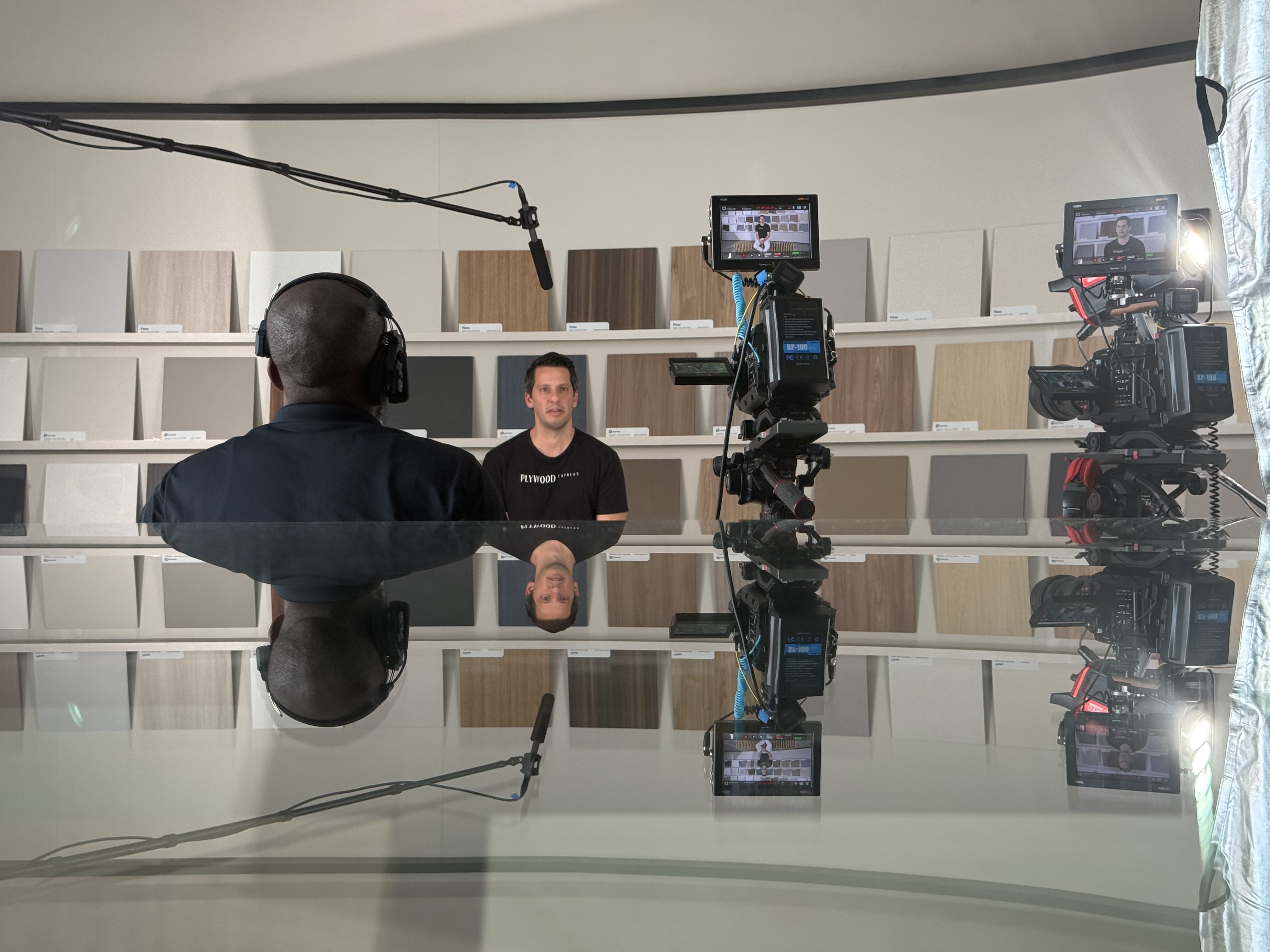 Plywood Express BTS interview — subject seated against wood sample wall