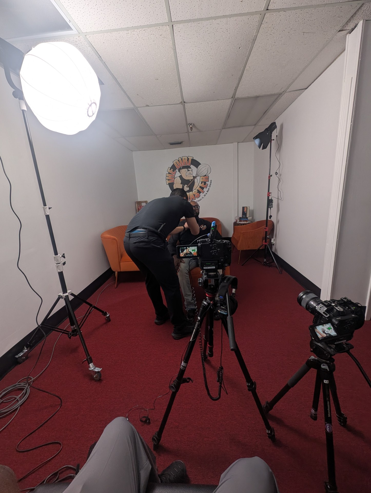 OBT NEXT — The Dirt Master, crew setting up camera with branded logo on wall behind interview chair
