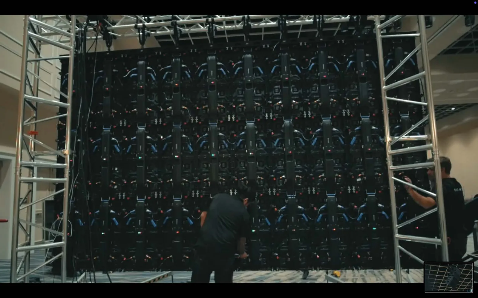 Crew assembling a large modular LED video wall on truss before a live event