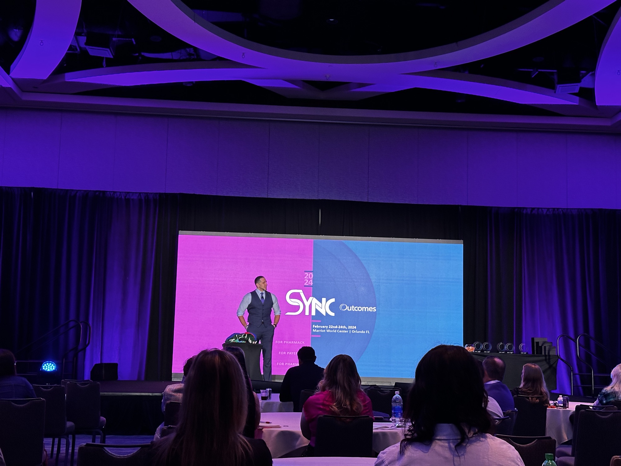 Outcomes SYNC Conference, presenter on stage during a session