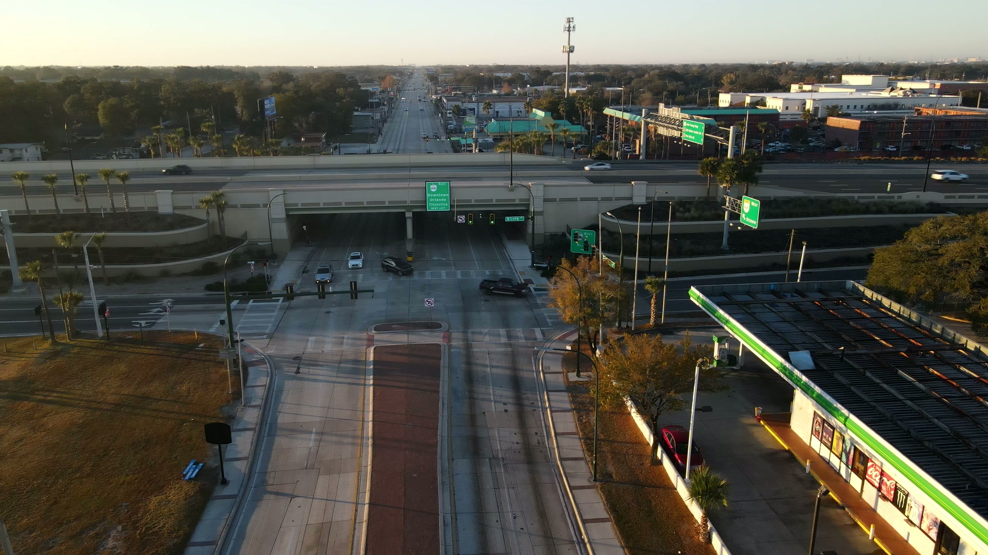 Sunrise drone shot pushing down Orange Blossom Trail toward a highway overpass, Orlando