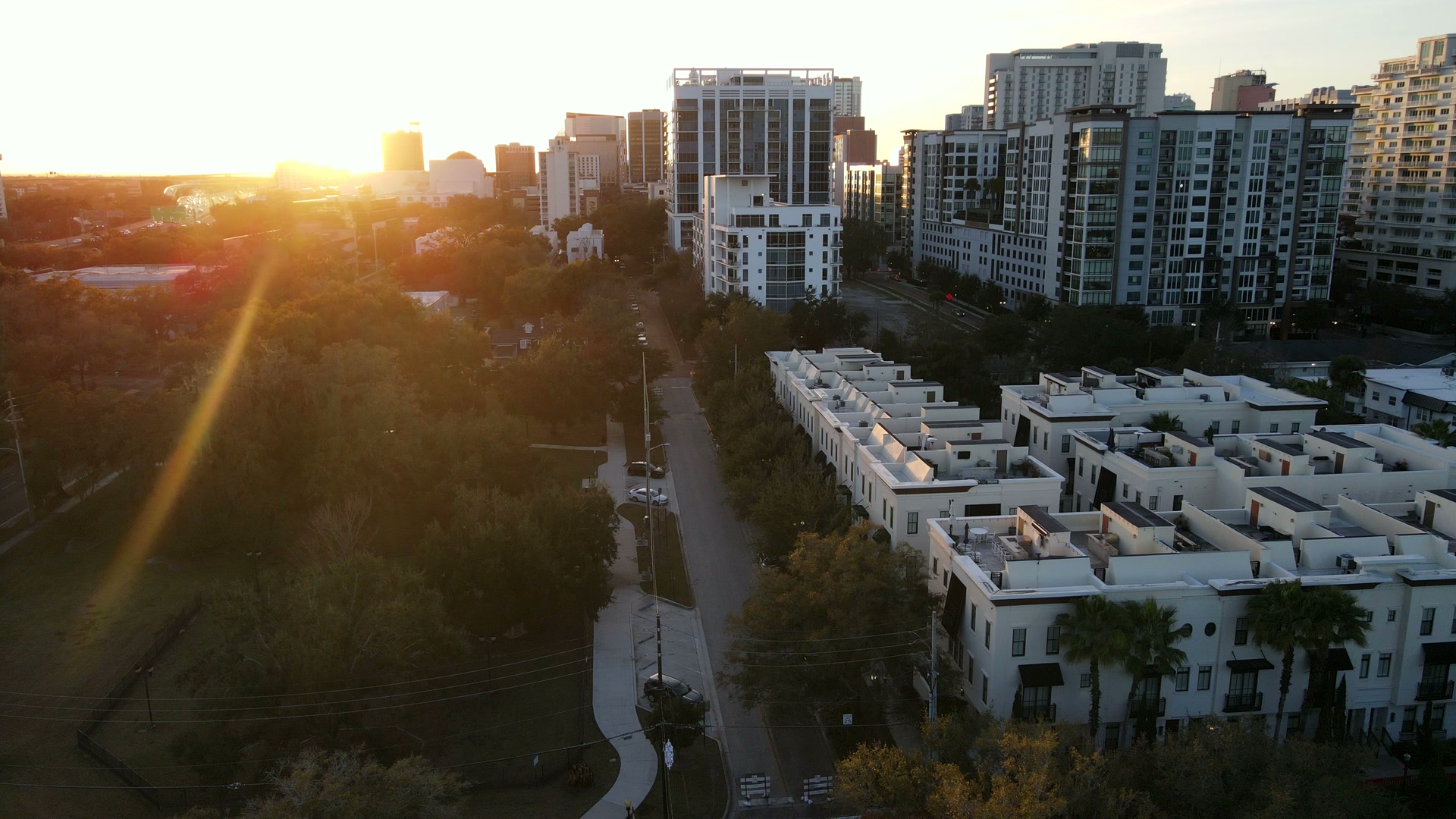 Sunset between downtown Orlando towers over townhomes, from above