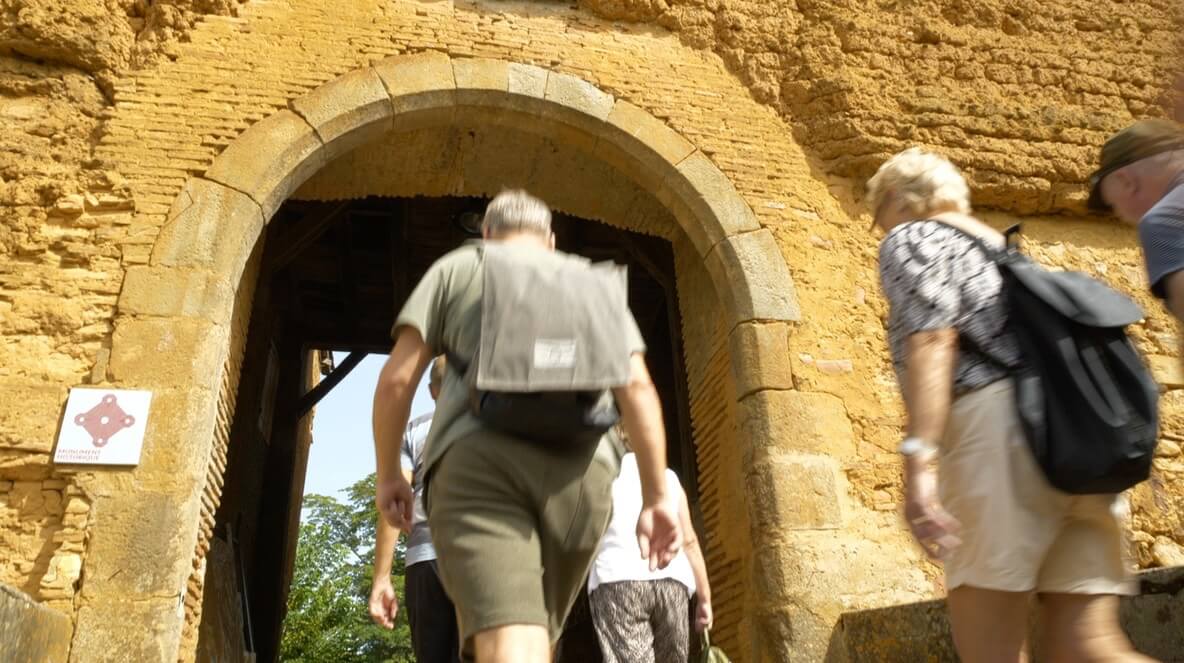 A man wearing a backpack walks through a doorway.