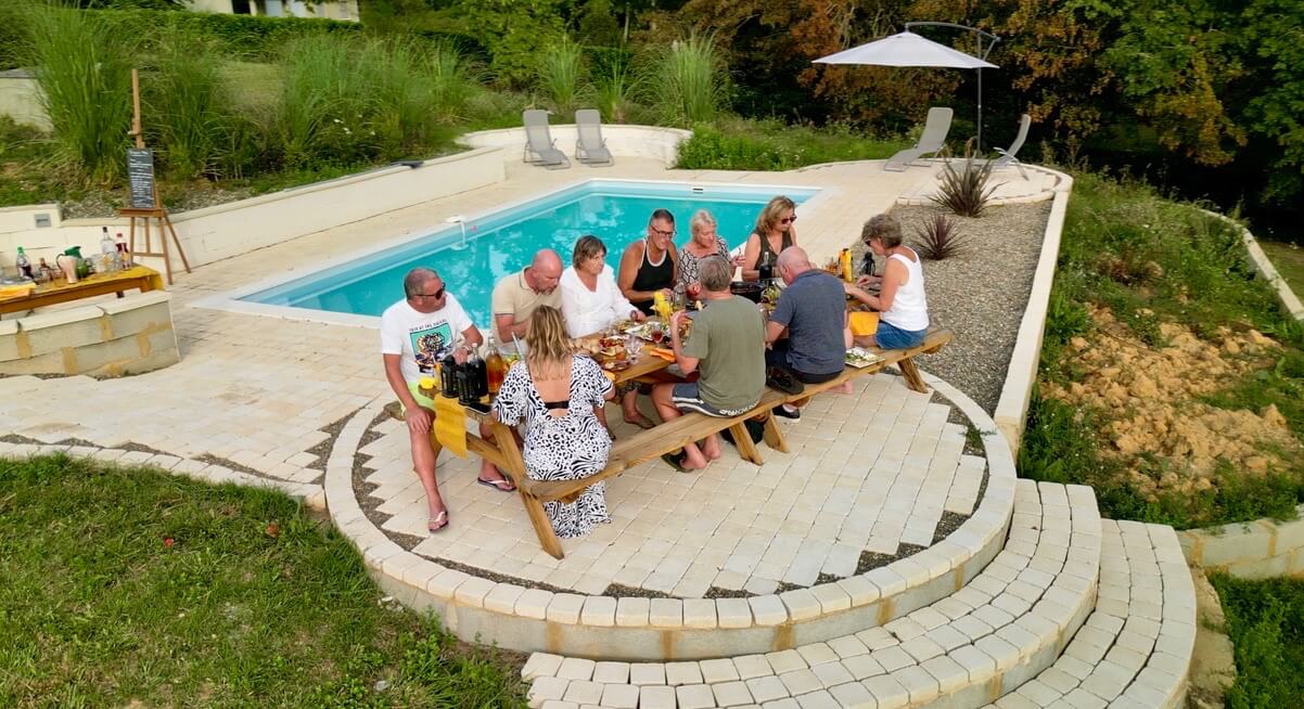 A group of people sitting around a table in a pool house.