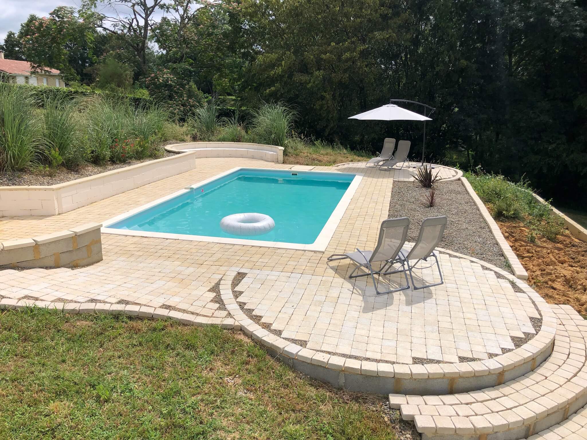 A large pool with a white chair and umbrella.